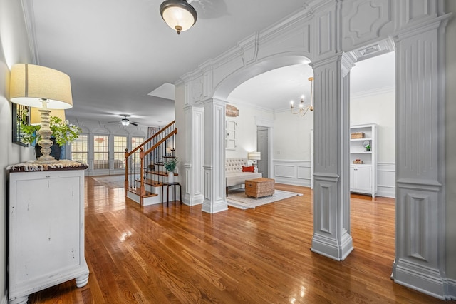 foyer with ornate columns, stairway, arched walkways, and a decorative wall