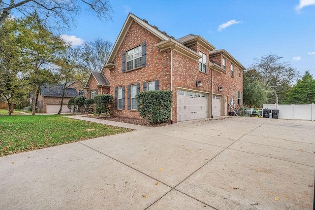 view of side of property with a garage, brick siding, fence, driveway, and a yard