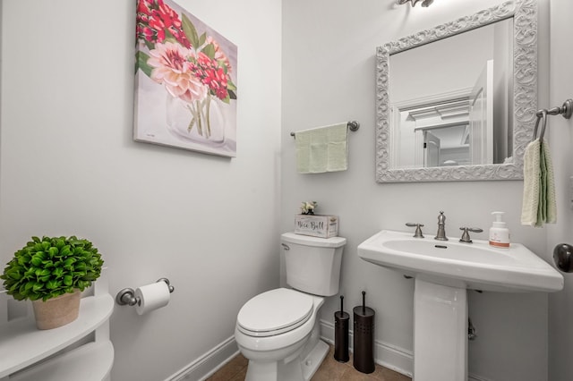 half bathroom with a sink, toilet, and baseboards