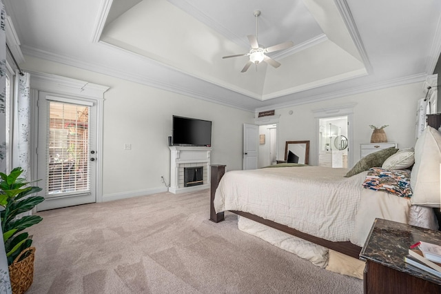 bedroom featuring light carpet, a fireplace, access to outside, ornamental molding, and a tray ceiling