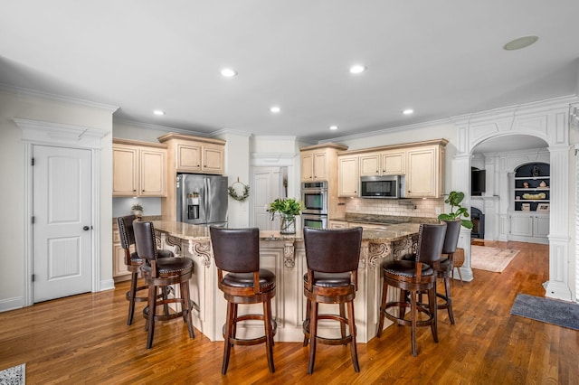 kitchen with stone counters, a center island, dark wood finished floors, a breakfast bar area, and appliances with stainless steel finishes