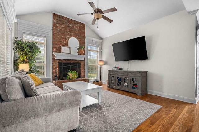 living area with baseboards, a ceiling fan, wood finished floors, vaulted ceiling, and a fireplace