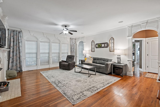 living room with ornamental molding, arched walkways, ceiling fan, and wood finished floors