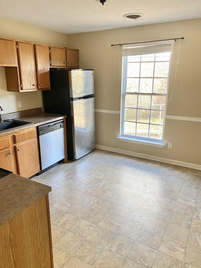 kitchen featuring stainless steel appliances, a sink, visible vents, and baseboards