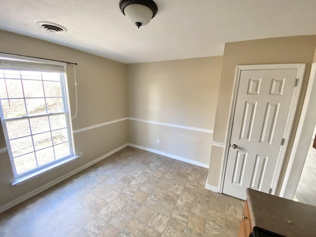 empty room featuring baseboards, visible vents, and a healthy amount of sunlight