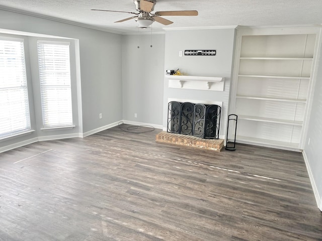 unfurnished living room with dark wood-style floors, crown molding, a brick fireplace, and a textured ceiling