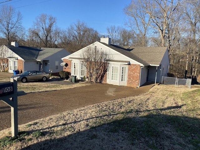 view of home's exterior featuring a yard, brick siding, a chimney, and fence