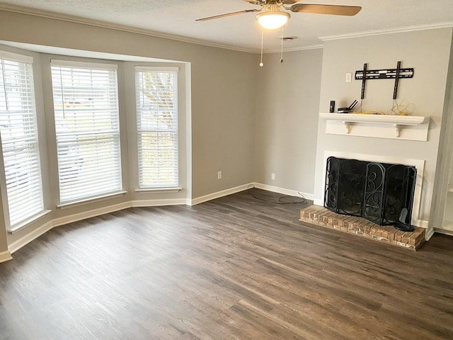 unfurnished living room with dark wood-style flooring, a ceiling fan, baseboards, a brick fireplace, and crown molding