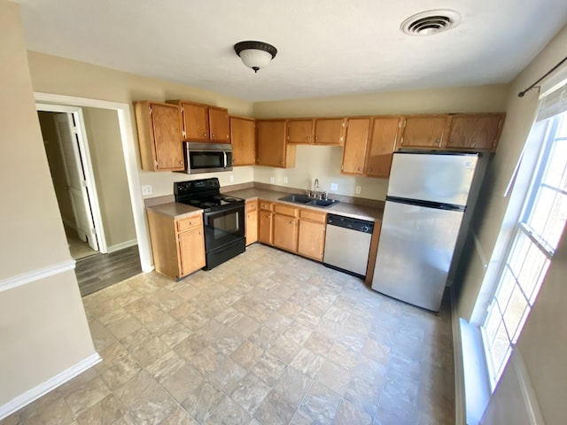 kitchen with appliances with stainless steel finishes, a sink, visible vents, and baseboards