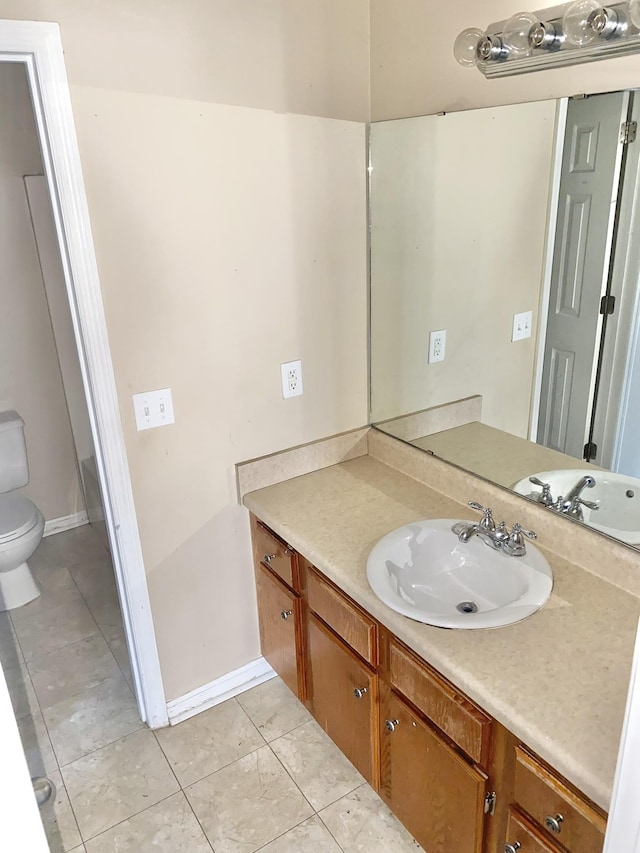 bathroom featuring toilet, vanity, baseboards, and tile patterned floors