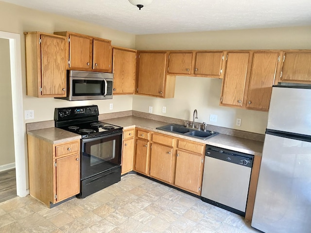 kitchen featuring brown cabinetry, appliances with stainless steel finishes, light countertops, and a sink