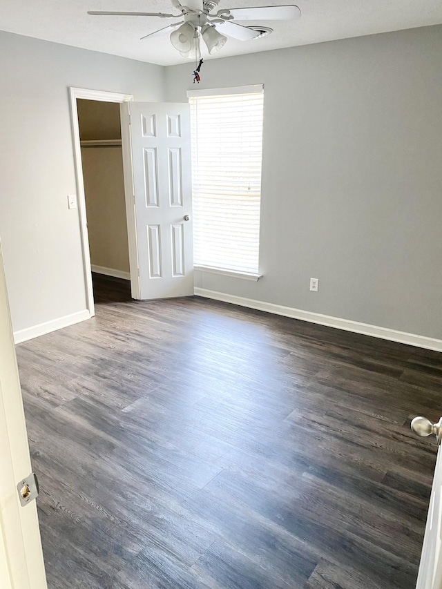 unfurnished bedroom featuring dark wood-type flooring, ceiling fan, and baseboards