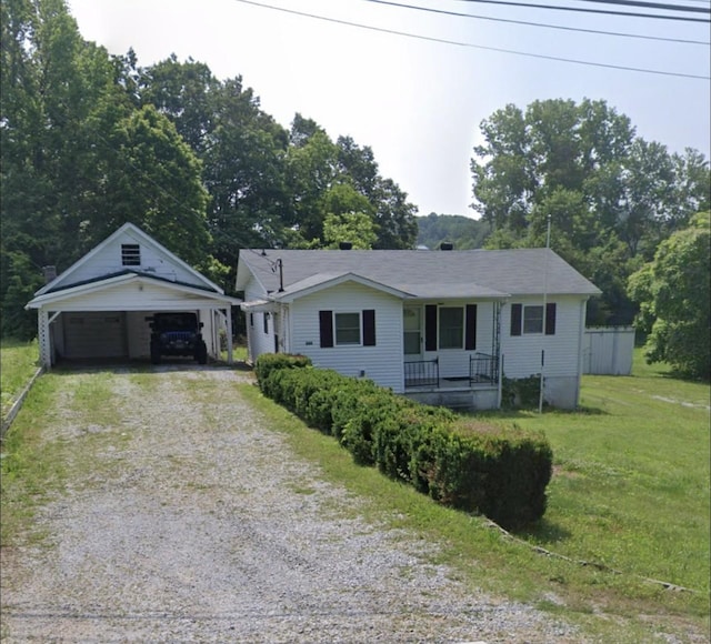 ranch-style house with an outbuilding, covered porch, driveway, and a front yard