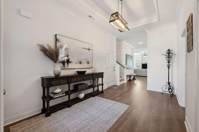 foyer with dark wood-style floors, crown molding, baseboards, and stairs