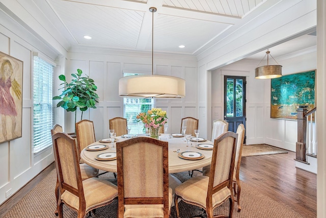 dining area with crown molding, a healthy amount of sunlight, and a decorative wall