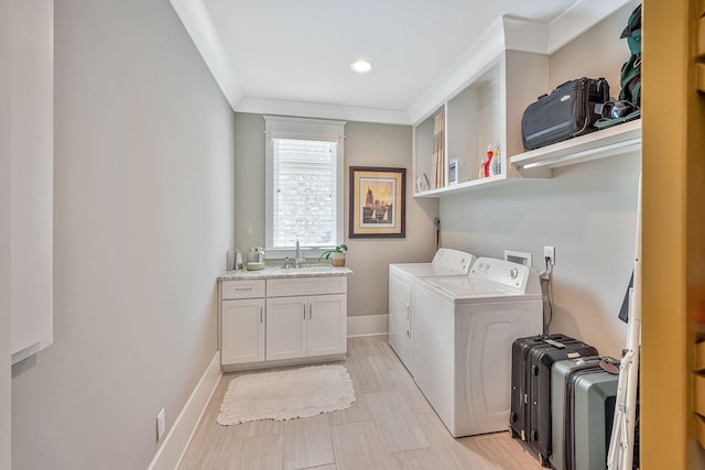 laundry room with cabinet space, baseboards, ornamental molding, washing machine and clothes dryer, and a sink