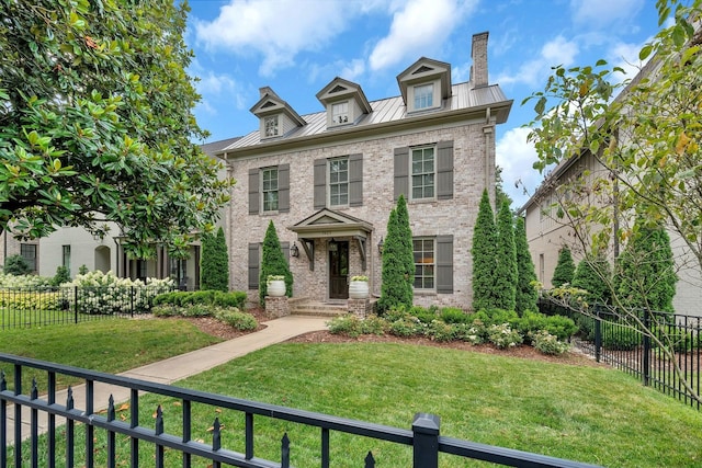 colonial-style house with fence private yard, a standing seam roof, brick siding, and a chimney