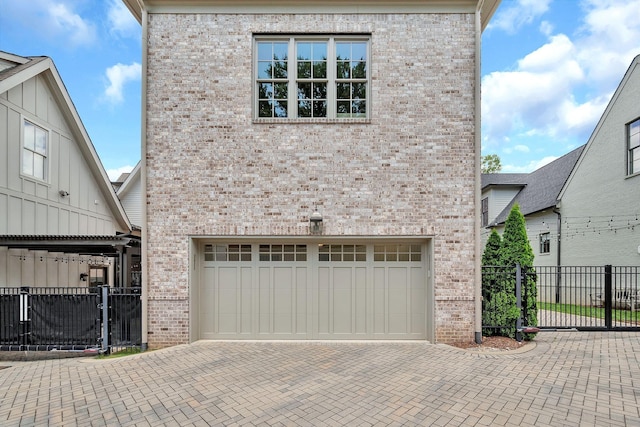 view of front of home with a garage, brick siding, fence, decorative driveway, and a gate