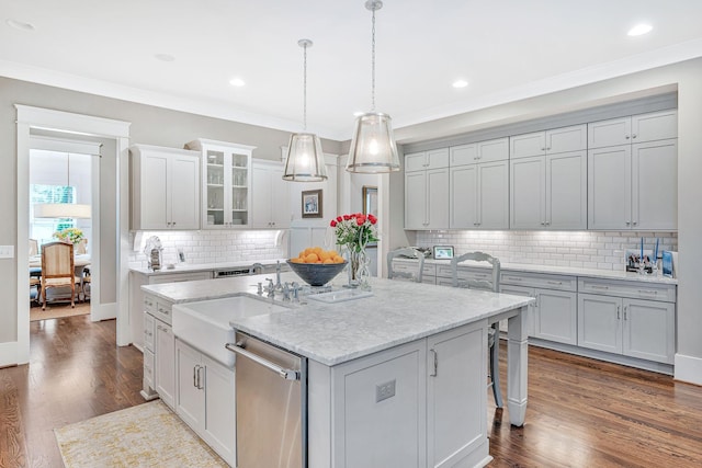 kitchen featuring dishwasher, glass insert cabinets, decorative light fixtures, a kitchen island with sink, and a sink