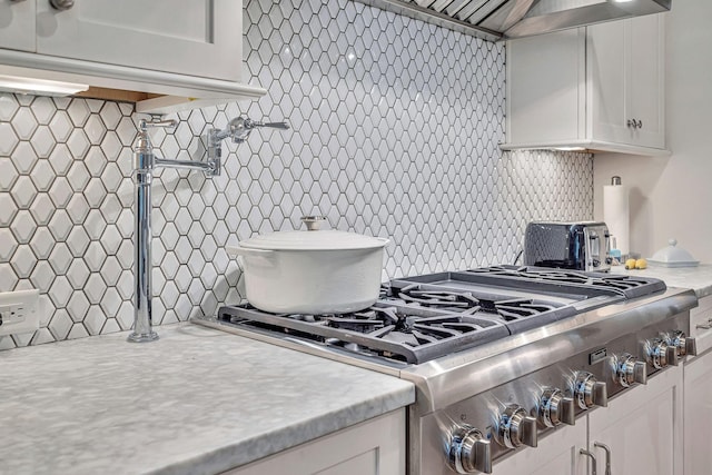 kitchen with range hood, white cabinets, and backsplash