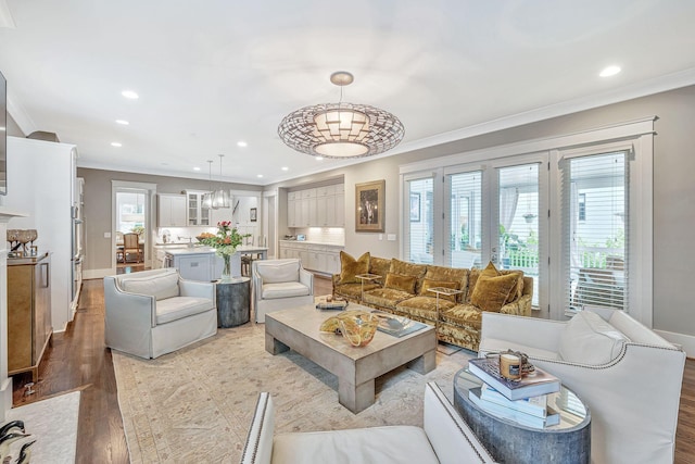 living area with light wood-style flooring, ornamental molding, baseboards, and recessed lighting