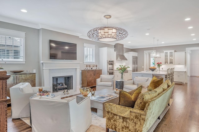 living area featuring ornamental molding, light wood finished floors, and a tiled fireplace