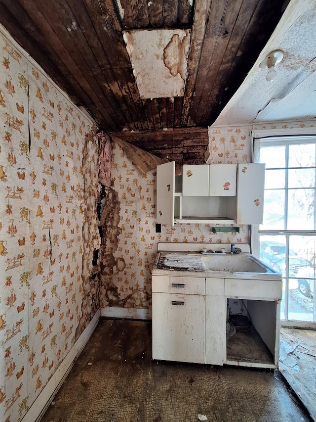 kitchen featuring wooden ceiling, a sink, and white cabinetry