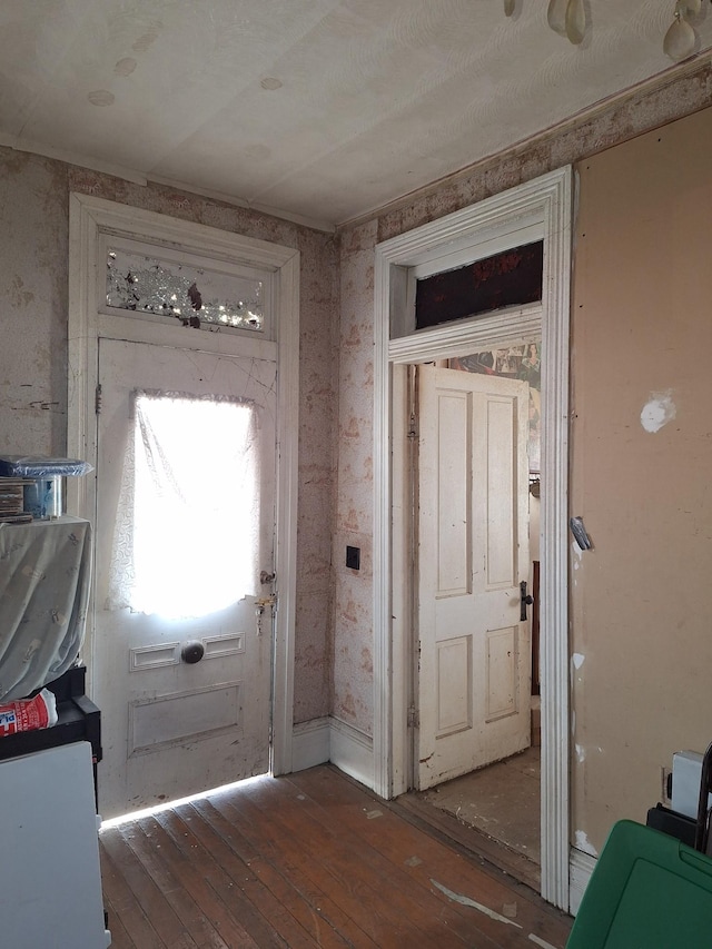 doorway with dark wood finished floors and wallpapered walls