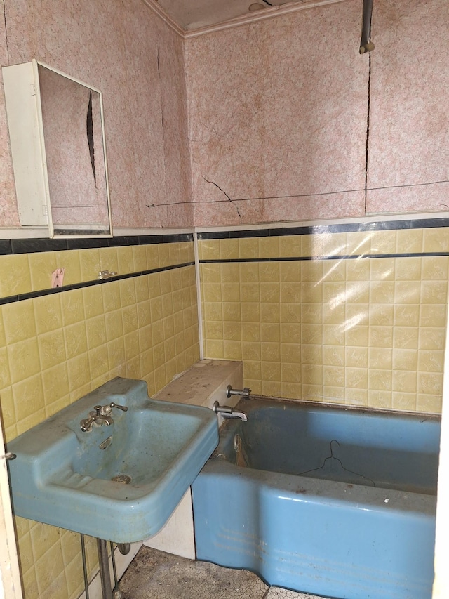 bathroom with a sink, a bathtub, and tile walls