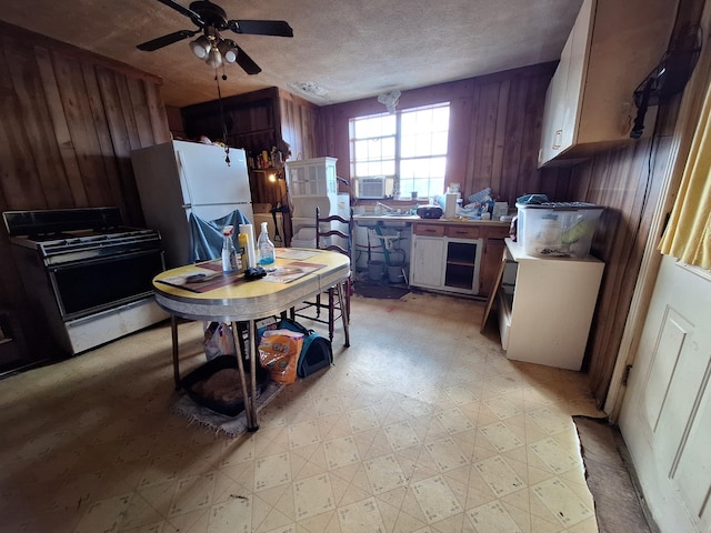 kitchen with range, ceiling fan, a textured ceiling, wood walls, and light floors