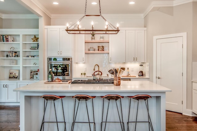 kitchen featuring light countertops, white cabinets, oven, and a center island with sink