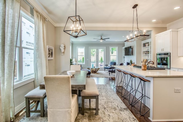 dining space featuring baseboards, dark wood-type flooring, crown molding, french doors, and ceiling fan with notable chandelier