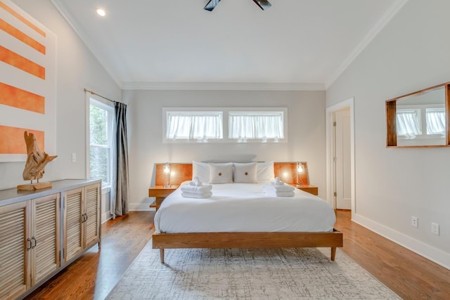 bedroom featuring ornamental molding, lofted ceiling, baseboards, and wood finished floors