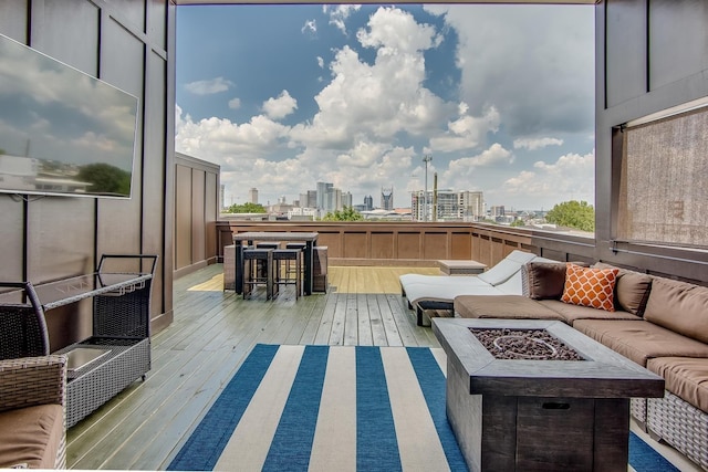 exterior space featuring a view of city, a deck, and an outdoor living space with a fire pit