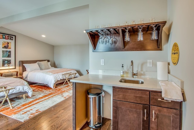 bedroom with lofted ceiling, dark wood-style flooring, indoor wet bar, and a sink