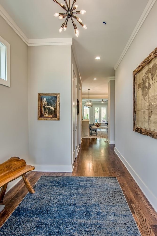 hall featuring ornamental molding, dark wood-type flooring, baseboards, and an inviting chandelier