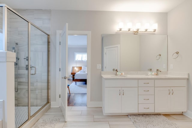 full bath featuring a stall shower, double vanity, a sink, and ensuite bathroom