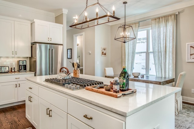 kitchen with stainless steel appliances, a kitchen island, white cabinets, hanging light fixtures, and crown molding