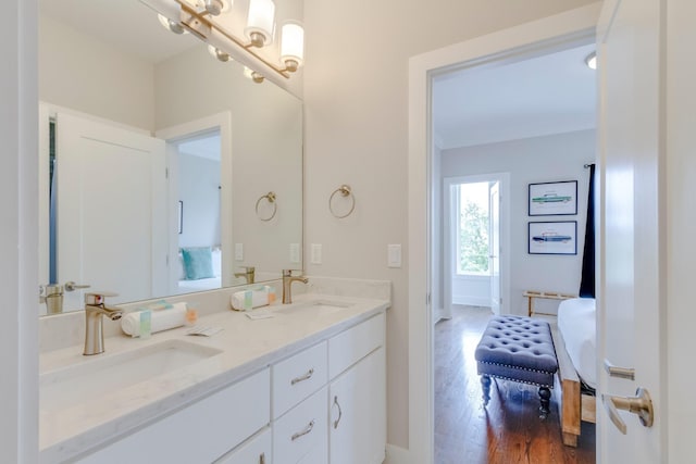 full bath with double vanity, connected bathroom, a sink, and wood finished floors