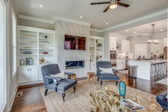 living room featuring dark wood-style flooring, recessed lighting, visible vents, a high end fireplace, and ceiling fan with notable chandelier