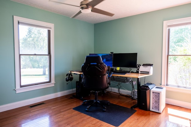 office space with a ceiling fan, baseboards, visible vents, and wood finished floors