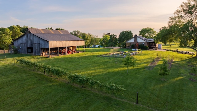 yard at dusk featuring an outbuilding, a barn, and a garden