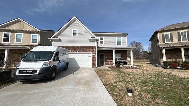 view of front of house with brick siding, a porch, a front yard, a garage, and driveway