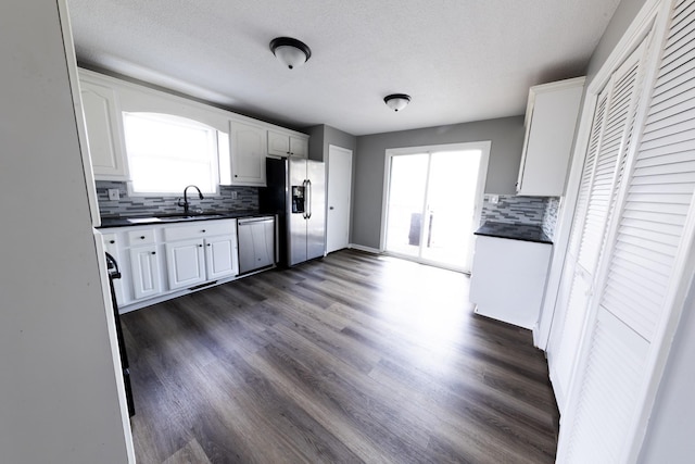 kitchen featuring appliances with stainless steel finishes, dark countertops, white cabinetry, and a sink