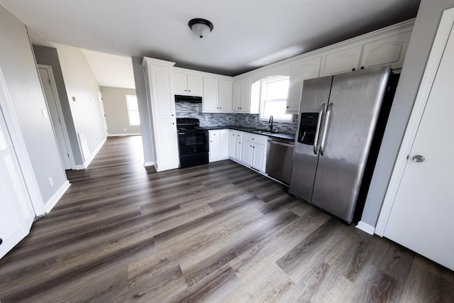 kitchen featuring dark countertops, appliances with stainless steel finishes, white cabinets, and a sink