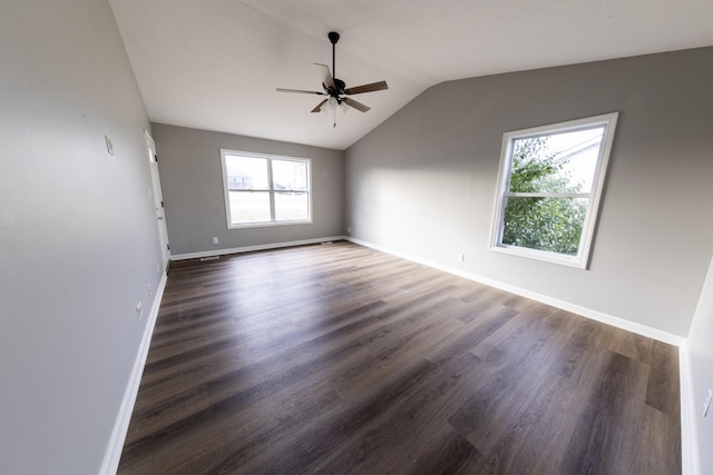 empty room with dark wood-type flooring, vaulted ceiling, baseboards, and a ceiling fan