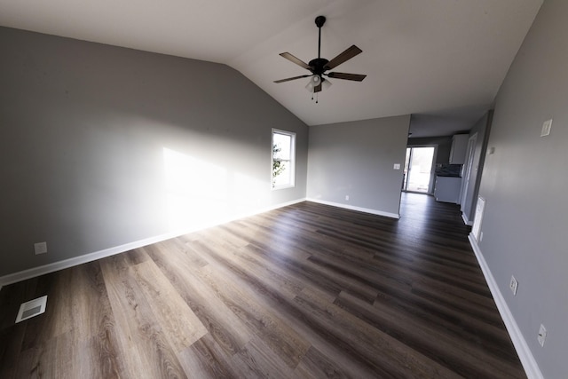 empty room with lofted ceiling, dark wood-style flooring, visible vents, and plenty of natural light