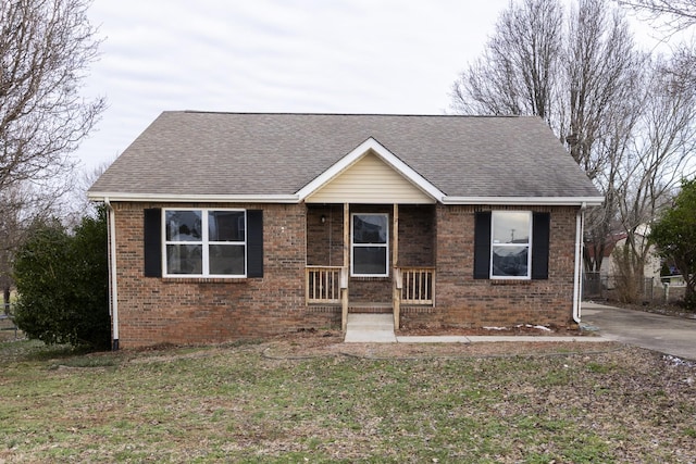 view of front of property featuring brick siding, roof with shingles, and a front yard