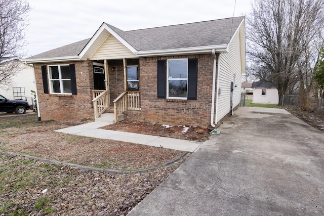 ranch-style home with an outbuilding, brick siding, and roof with shingles