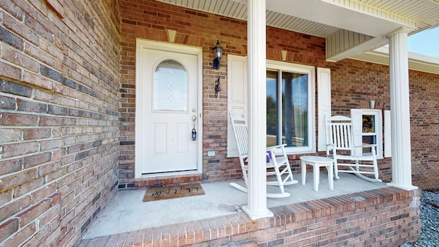 property entrance featuring covered porch and brick siding